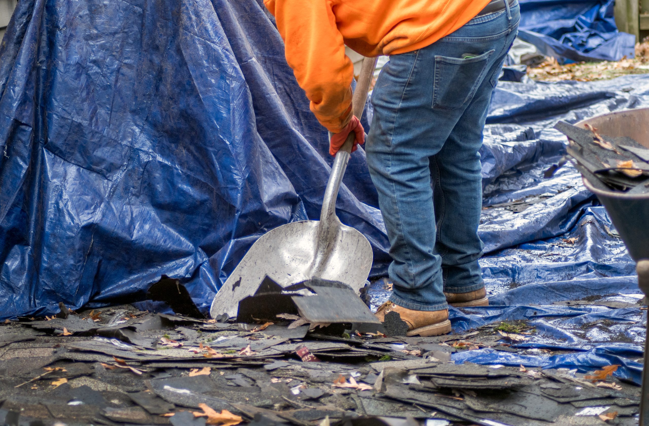 Roofer cleaning debris from residential roof